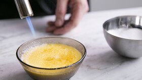 A baker caramelising the sugar atop a creme brulee with a blow torch